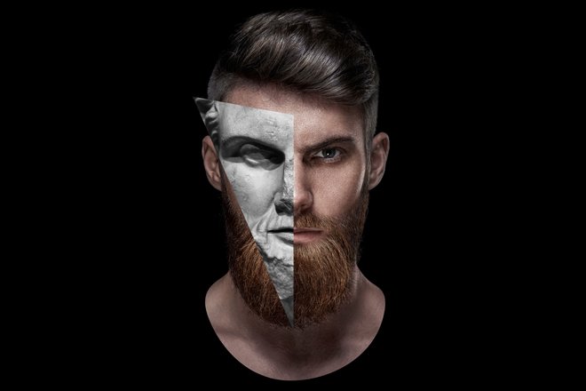 Foto: Portrait eines jungen Mannes isoliert vor schwarzem Hintergrund der zuversichtlich in die Kamera sieht.