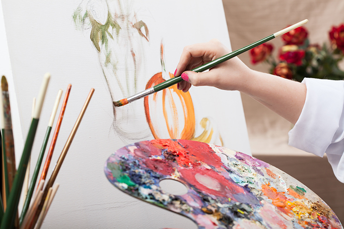 A closeup of an artist with a brush painting a picture