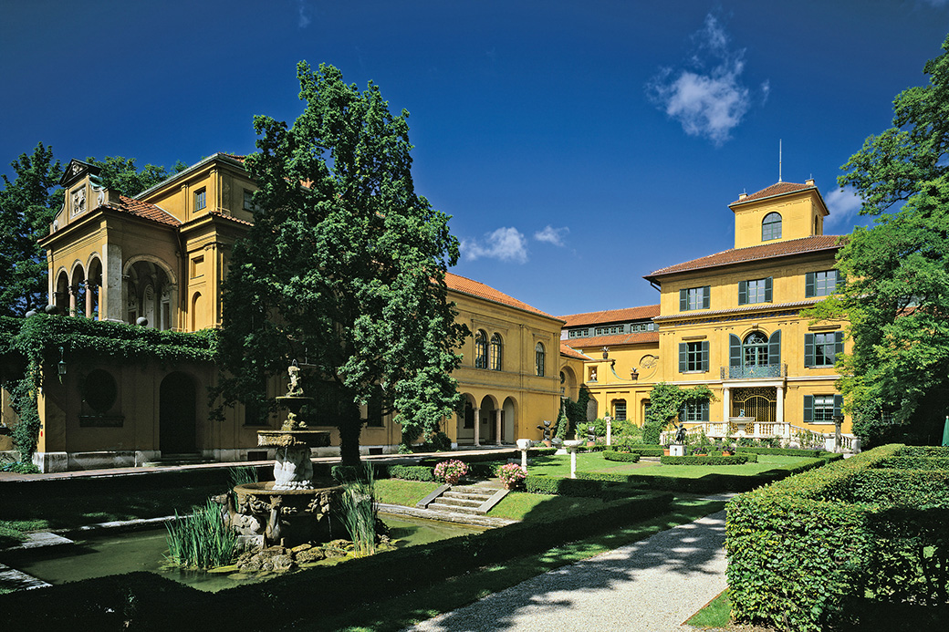 Die Städtische Galerie im Lenbachhaus in der historischen Villa des Malerfürsten Franz von Lenbach gehört zu den schönsten Orten Münchens. Sie ist außerdem Teil des umfassenden Kunstareals in der Münchner Maxvorstadt, das insgesamt 16 Museen umfasst – darunter auch die Pinakotheken, das Museum Brandhorst und die Glyptothek. Gäste des Lenbachhauses können diese Pracht des nach italienischen Vorbildern errichteten Anwesens noch heute erleben. Der idyllische Garten mit seinen plätschernden Brunnen ist ebenso eine kleine Oase wie die Räume der Künstlerresidenz, deren intime Proportionen auch nach dem Umbau durch das renommierte Architektenbüro Foster + Partner bewahrt wurden. The Städtische Galerie im Lenbachhaus (Lenbachhaus art gallery) is housed in the historic villa that once belonged to master painter Franz von Lenbach and one of the most beautiful spots in Munich. It is also part of the extensive art area in Munich's Maxvorstadt, which comprises a total of 16 museums - including the Pinakotheken, the Museum Brandhorst and the Glyptothek. Even today, visitors of the Lenbachhaus can still marvel this majestic building, which was inspired by the Italian style. Its idyllic garden and bubbling fountains offer a small piece of paradise, just like the rooms in the artist’s residence, whose intimate atmosphere was carefully maintained during the renovations by renowned architects Foster + Partner.